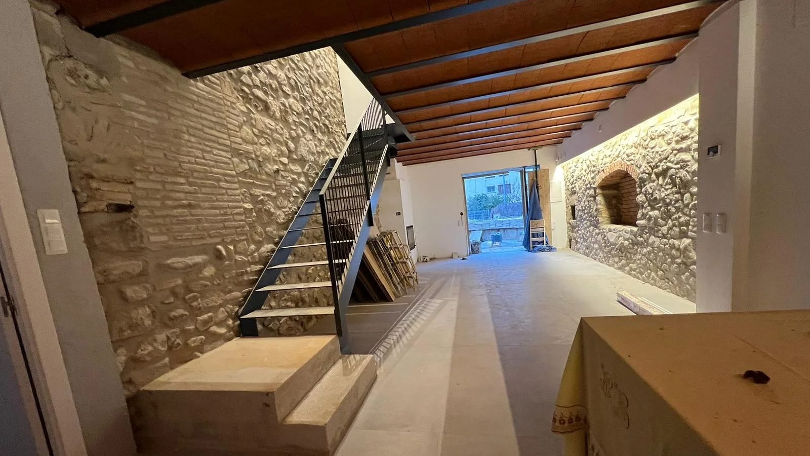 Rehabilitación interior con pared de piedra vista y escalera metálica de Grupo RUF 93