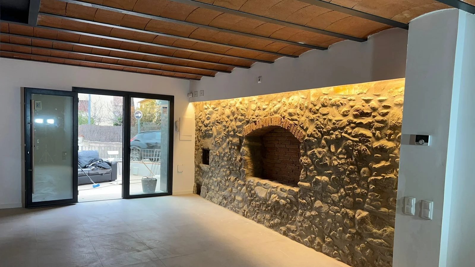 Salón rehabilitado con pared de piedra vista y vigas de madera por Grupo RUF 93